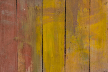 Old, cracked planks, chaotically painted yellow and red.