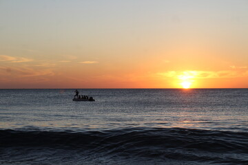 Puesta del Sol con su gente y las olas del mar