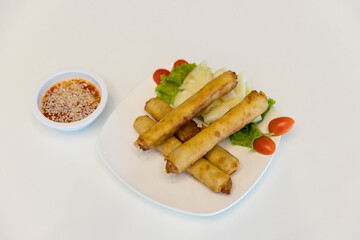 Fried spring rolls with red and white sauces. Deep fried spring roll with sauce on white plate. Crispy spring rolls on dish with vegetable. Fried Chinese Traditional Spring rolls food.