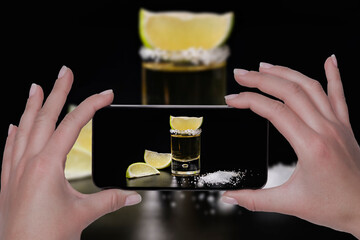 Holding a phone showing a tequila shot with lemon slices