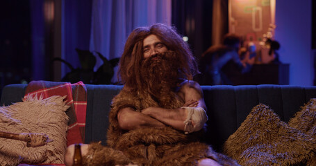 Prehistoric time traveler wild caveman in animal fur pising at camera smiling looking confident...