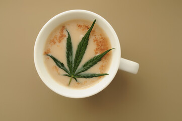 Marijuana cappuccino with cinnamon. Cup of organic CBD coffee. Cannabis kitchen. Hot drink isolated on brown background, flat lay, top view.