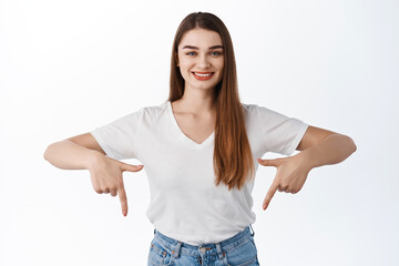 Smiling confident girl pointing fingers down, showing advertisement bellow, click this link, check...