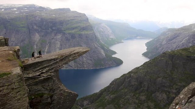 Hikers On Cliff Jut Of Trolltunga Rock Formation In Vestland County, Norway. Wide