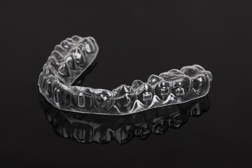 Invisible orthodontics cosmetic brackets on black background. Tooth aligners, for beautiful smile.