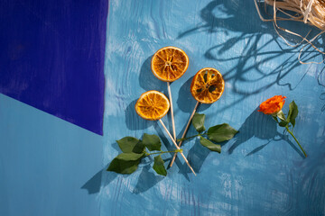 Flower made from dried orange slices on blue wooden background with nice shadows and copy space, greeting card concept