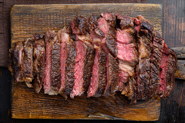 Sliced grilled meat steak Rib eye medium rare, on wooden serving board, on old dark  wooden table...