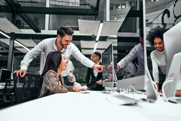 Fun at work. Two colleagues laughing looking at the computer screen. Break, ease at work.