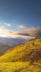 colorful landscape seen from the top of the mountain range showing hills, blue sky, some clouds