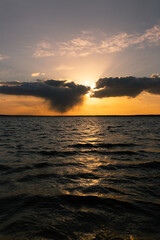 Naklejka premium Beautiful, colorful sunset over the lake. The twilight rays of the sun are reflected in the water. Sun and solar path on water in the centre. 