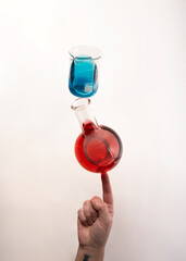 Flat bottom flask and a Berzelius beaker glass balanced on top of fingertip