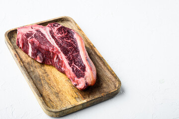 Raw marbled meat , T bone cut, on white stone  background, with copy space for text