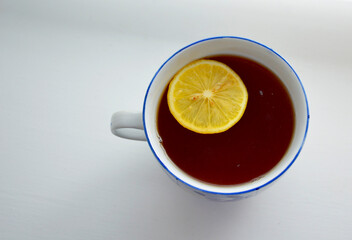 there is a large mug with hot tea on a light background, a lemon slice is floating in the mug