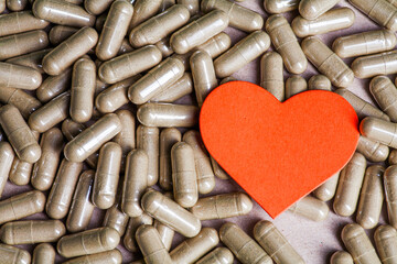 Heart supporting plant medicine. Paper heart is set on top of herbal capsules