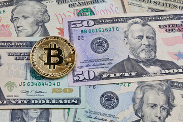 Close-up on a golden bitcoin coin on top of a stack of us dollars.