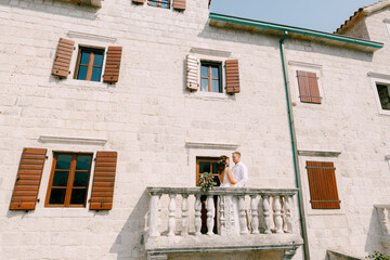 The bride and groom embrace on the wide balcony of an old building in ancient town in Montenegro