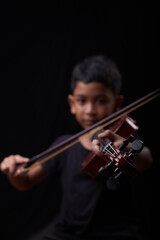 Young boy play the violin on black background