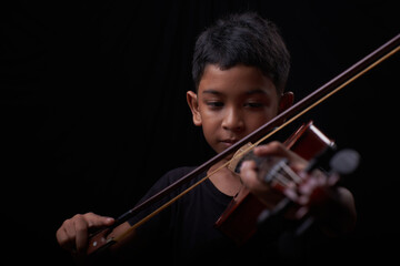 Young boy play the violin on black background