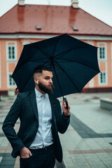 Businessman holding a black umbrella in the city