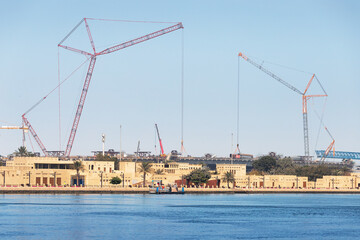 Fototapeta na wymiar Numerous industrial cranes are involved in the construction of a road interchange and bridge in the Bur Dubai and Creek area, UAE