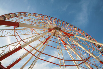 A large red and white Ferris Wheel against a blue sky