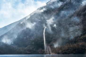 Fire of the Mondonico Mountain above Lake Ghirla with a helicopter that loading water for extinguishing, Valganna, Lombardy, Italy.