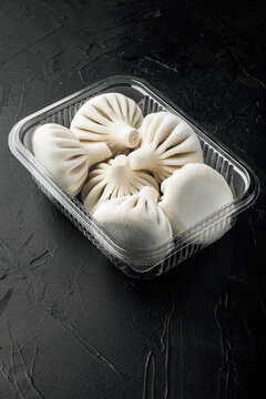 Khinkali Dumplings with beef and lamb meat, in plastic tray, on black stone background, with copy space for text