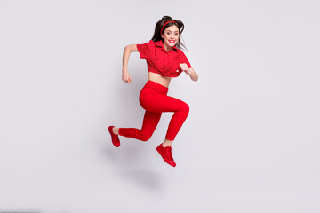 Full length photo of charming shiny young woman dressed pin-up outfit running jumping high isolated grey color background