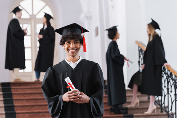 African american bachelor with diploma smiling at camera