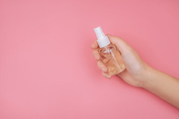 Woman hands holding, essential oil, serum, lotion and cream 
оn pink background. Beauty and cosmetic concept.