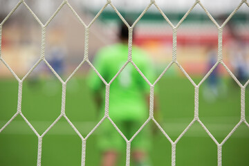 Fototapeta premium out of focus goalkeeper stands behind the football net in the stadium