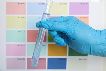 Fototapeta premium Doctor holding test tube with liquid near sample chart, closeup