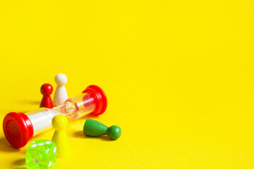 Layout of board games on a yellow background: dice, chips, hourglass timer. Entertainment at home for children and adults. Copy space