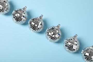 Shiny disco balls on light blue background, flat lay