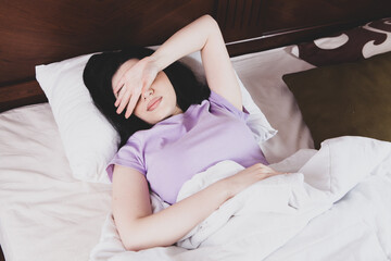 girl lying in bed suffering from stomach pain