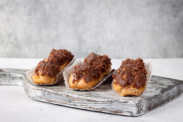 Three chocolate eclairs on the old wooden board, free space for text