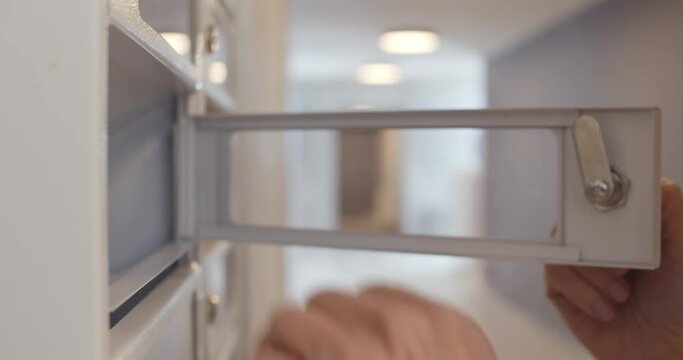 Close-up of hand insert key to unlock mailbox locker in apartment and take correspondence