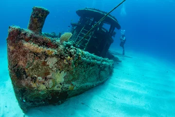 Fotobehang Schipbreuk Woman diver on the wreck of a small tugboat off Grand Case on the French island of St Martin  © timsimages.uk