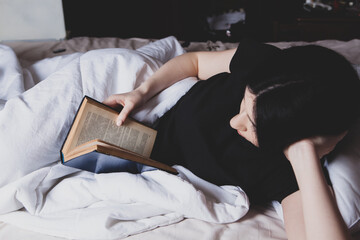young girl reading a book in bed