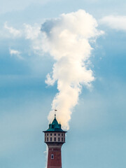 Chimney smoke over watertower in Mannheim Germany, blue sky in background