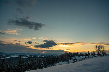 Fototapeta premium Panorama of a village in winter in the mountains at sunset