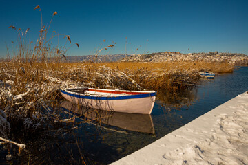 OHRID, NORTH MACEDONIA: A wooden boat sits in the thick grass on a lake in Ohrid in winter.
