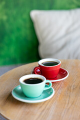 coffee in red and mint cups, on a wooden table. americano, espresso, cappuccino, black coffee start of the day