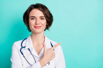 Photo of young woman doctor happy positive smile indicate finger empty space ad advice clinic...
