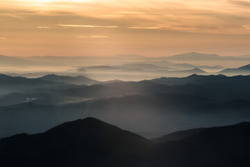 Fototapeta na wymiar Mist and fog between valley and layers of mountains and hills at sunset, in Umbria Italy