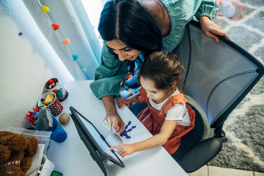 Mom Helping Daughter Look At Something On IPad Tablet Computer