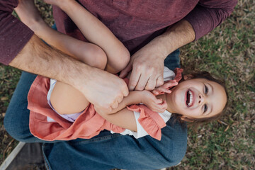 Dad tickling laughing daughter in his lap