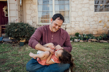 Dad tickling laughing daughter in his lap