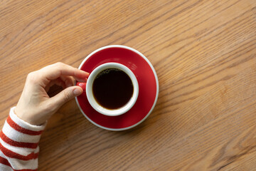 Women's hands holding a red cup of coffee. coffee shop, pastry shop for socializing and enjoying coffee, a breakfast drink. soft selective focus