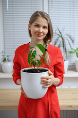 Girl transplanting plants at home in white pots